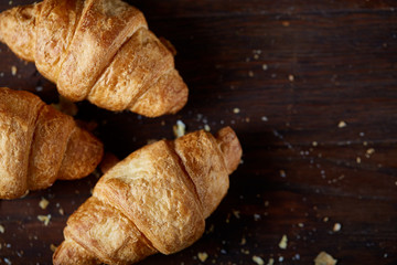 Tasty buttery croissants on an old wooden table, close-up, selective focus, shallow depth of field.