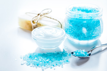 Fototapeta na wymiar blue sea salt, soap and body cream on white desk background