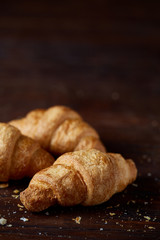 Tasty buttery croissants on an old wooden table, close-up, selective focus, shallow depth of field.