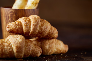 Tasty buttery croissants on an old wooden table, close-up, selective focus, shallow depth of field.