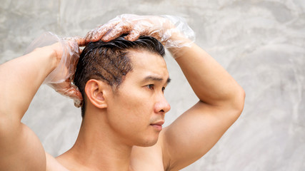 Asian men dye his hair color on a gray background.