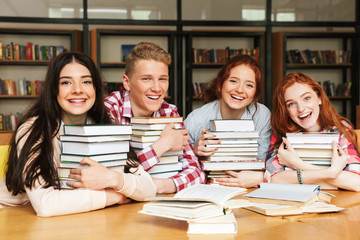 Group of happy teenagers sitting at the library