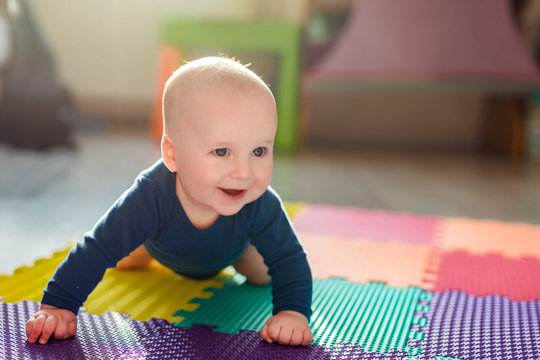 Infant Baby Boy Playing On Colorful Soft Mat. Little Child Making First Crawling Steps On Floor. Top View From Above