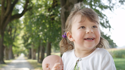 CLOSE UP: Playful little girl with adorable face jumps around sunny avenue.