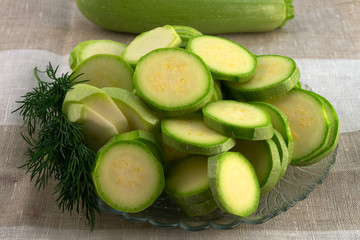 Round zucchini slices, laid out in an arbitrary shape on a glass plate with green dill.