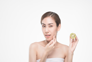 Fototapeta na wymiar beautiful asia woman with towel on head with perfect clean skin smiling holding kiwi slices over white background. Beauty cosmetology and spa.