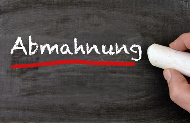 Hand schreibt Abmahnung auf Kreidetafel