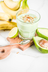Healthy summer drink, avocado and banana smoothie with lime, granola and coconut milk, dark rusty background copy space
