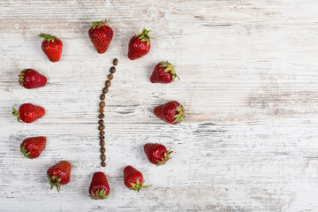 strawberry clock with arrows from coffee beans showing the time 12:30 on a wooden vintage board
