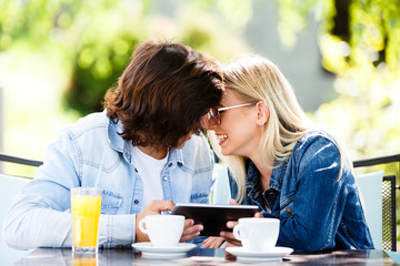 Young couple using tablet while sitting together at cafe