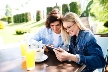 Young couple using tablet while sitting together at cafe