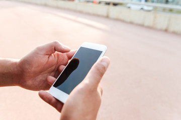 Cropped photo of young sports man using mobile phone.