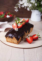 Whole-grain cake with strawberries/ Whole-grain cake with chocolate icing and strawberries on a wooden stand