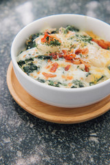 Close up of spinach with cheese in a dish on wooden board