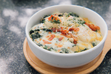 Close up of spinach with cheese in a dish on wooden board