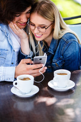 Young couple using headphones and smartphone for fun while sitting together