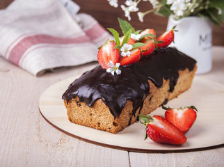 Whole-grain cake with strawberries/ Whole-grain cake with chocolate icing and strawberries on a wooden stand