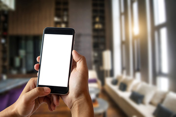 A man hand holding smart phone device in the bright office room interior.