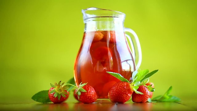 Sweet compote of ripe red strawberries in a glass decanter on a table