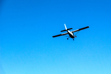 Fototapeta na wymiar Small plane flies against a blue sky background close-up