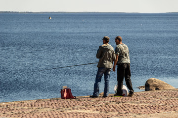 Two men fishing on the waterfront of the city