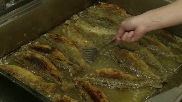 Fish fried in a frying pan until golden brown,Pieces of fresh fish are fried in a frying pan in flour and they are turned with a fork.Chef is cooking fish.Preparing of fish for frying.