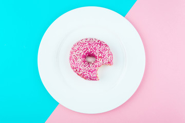 Minimalism, colour contrast on a blue and pink background, donut photo from above in flat style