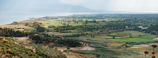 Summer rural landscape of Western Greece. Green forest on hillsides and house with red roofs on...