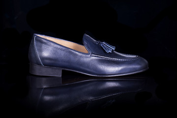 Blue men loafers shoes on black background with reflection. Fashion advertising shoes photos.