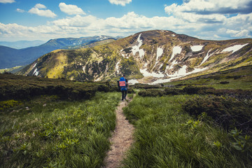 Obraz premium A tourist walks along a mountain meandering trail