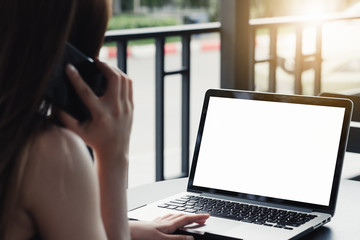 Mockup image of a businesswoman using laptop with blank white desktop screen with coffee cup on wooden table in cafe