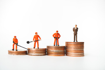 Miniature people, businessman and engineers standing on stack coins using as business and financial concept