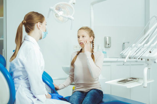 Have a problem. Attentive dentist listening to her patient and sitting in semi position