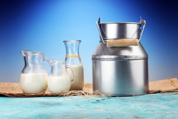 A jug of milk and glass of milk on a wooden table