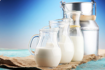 A jug of milk and glass of milk on a wooden table