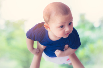 Happy baby play flying on mother hand