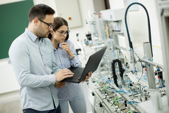 Young couple of students with laptop at robotics lab