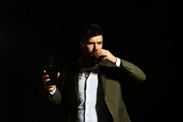 Man holding glass of whiskey or bourbon and bottle