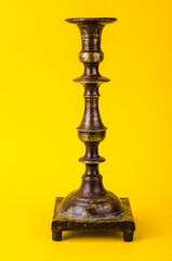Fototapeta na wymiar Vintage bronze candlestick on yellow background