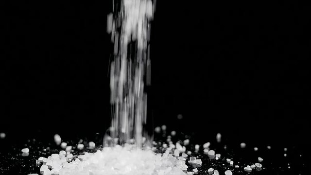 coarse sea salt crystal falling on black background
