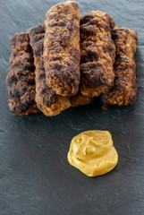 delicious grilled minced meat rolls mici ori mititei traditional romanian and balkan dish served with mustard on a black slate