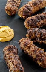 delicious grilled minced meat rolls mici ori mititei traditional romanian and balkan dish served with mustard on a black slate