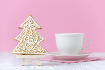 christmas tree gingerbread on the painting easel with coffe cup on pink background