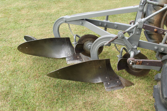 A Vintage Agricultural Farming Plough on a Tractor.