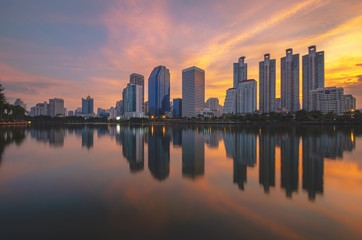 Fototapeta premium cityscapes building in modern skyline city at morning twilight golden hour with sunrise and water reflection.
