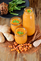 Yellow smoothie with berries of sea buckthorn in glass jars decorated with mint