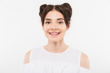 Portrait closeup of beautiful teenage girl 20s with double buns hairstyle and dental braces smiling at camera in happy mood, isolated over white background