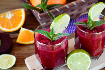 Smoothie with beet and orange in a glass decorated with mint and a slice of lime