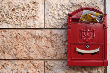 red mailbox with advertising on tiled wall with pink marble
