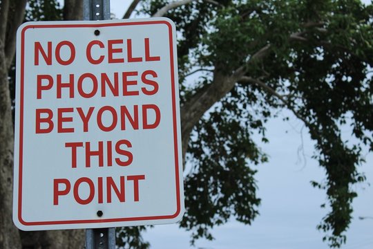 no cell phones beyond this point metal sign on post